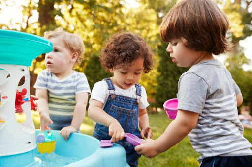 Group Of Young Children Playing With Water Table In Garden daycare facilities near me in san francisco ca
